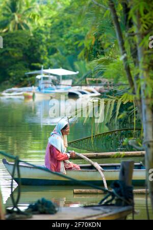 Filipina boatwoman in una piccola canoa di Outrigger. Fiume Loboc, Bohol, le Filippine. Foto Stock