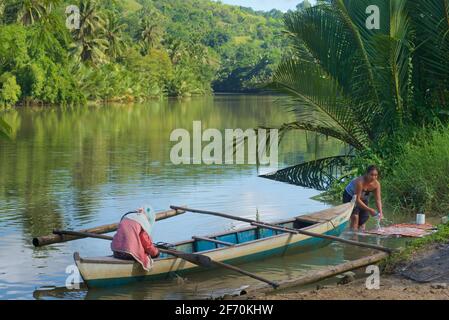 Piccola canoa Outrigger per traversate del fiume come un traghetto locale. Lavaggio nel fiume. Fiume Loboc, Bohol, Visayas Centrale, Bohol, Filippine. Foto Stock