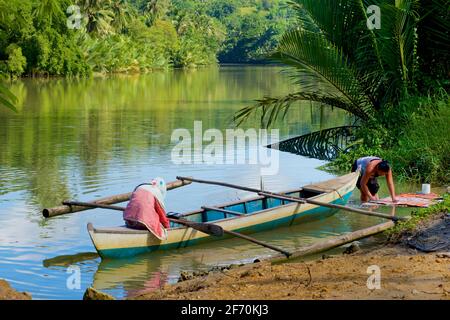 Piccola canoa Outrigger per traversate del fiume come un traghetto locale. Lavaggio nel fiume. Fiume Loboc, Bohol, Visayas Centrale, Bohol, Filippine. Foto Stock