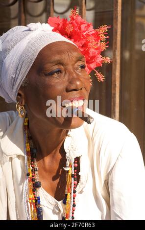 Fumatore di sigari donna cubana in abbigliamento bianco tipico di quelli che seguono la religione di Santeria. L'Avana. Habana, Cuba Foto Stock