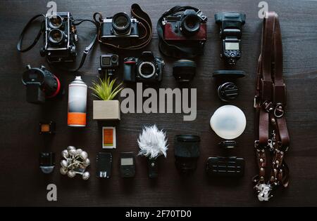 vista dall'alto del fotografo di matrimoni dello spazio di lavoro. Set di fotocamere digitali e analogiche, flash, accessori per fotocamere su sfondo scuro. Concetto di lavoro. Foto Stock