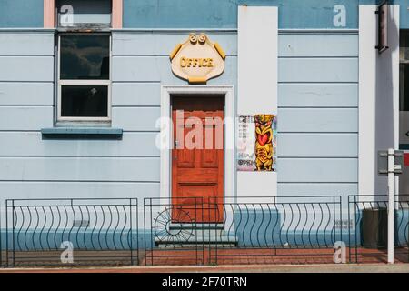 Una porta di legno e un cartello 'Office' sul lato di un edificio di colore blu a Waipukurau, Nuova Zelanda Foto Stock