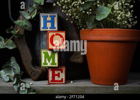 'Home' scritto in blocchi di legno d'epoca con sfondo rustico. Foto Stock