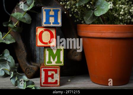 'Home' scritto in blocchi di legno d'epoca con sfondo rustico. Foto Stock