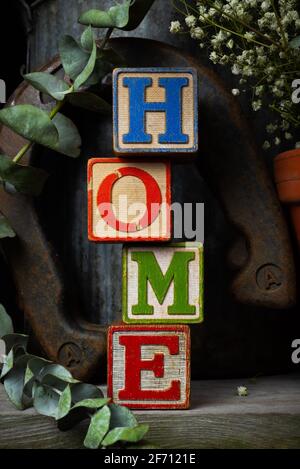 'Home' scritto in blocchi di legno d'epoca con sfondo rustico. Foto Stock