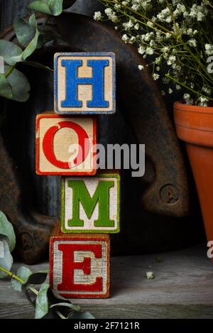 'Home' scritto in blocchi di legno d'epoca con sfondo rustico. Foto Stock