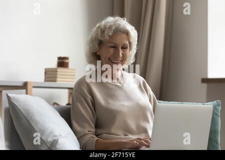 Buona donna anziana che effettua una videochiamata su un computer portatile da casa Foto Stock