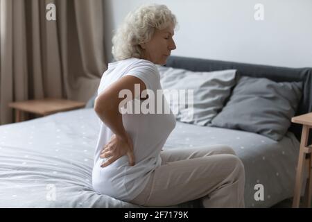 Donna anziana stanca che sente forte mal di schiena inferiore Foto Stock