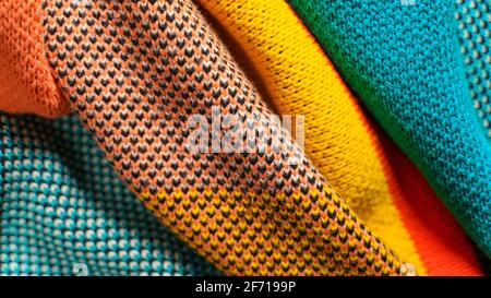 Una pila di tessuti a maglia colorati di diverse strutture e texture. Sfondo con forme uniformi. Tessuti a maglia multicolore piegati lisci Foto Stock