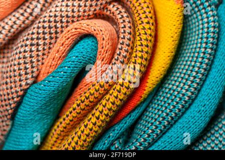 Pieghe ritorte di tessuti colorati a maglia di abiti invernali con strutture e tessuti diversi. Sfondo con forme uniformi. Multi colo piegato liscio Foto Stock