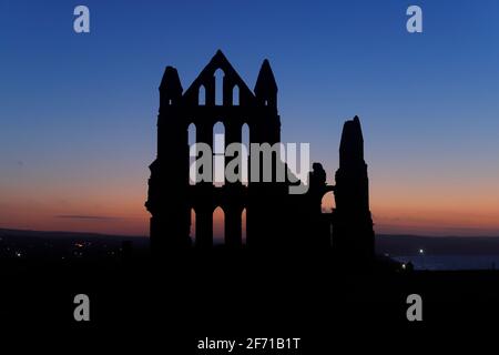 Whitby Abbey silhouette al tramonto a Whitby, North Yorkshire, UK Foto Stock