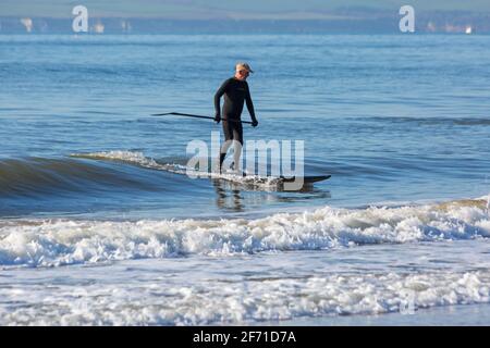 Poole, Dorset UK. 4 aprile 2021. Domenica di Pasqua. Tempo nel Regno Unito: Un inizio di giornata al sole che sembra essere un giorno pieno di sole e cielo blu, mentre la gente si dirige verso il mare a Poole spiagge per il lungo week-end di Pasqua in riva al mare. Paddleboarder godendo la pace prima che si affolgerà più tardi. Credit: Carolyn Jenkins/Alamy Live News Foto Stock