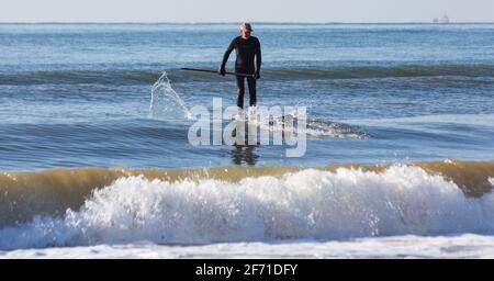 Poole, Dorset UK. 4 aprile 2021. Domenica di Pasqua. Tempo nel Regno Unito: Un inizio di giornata al sole che sembra essere un giorno pieno di sole e cielo blu, mentre la gente si dirige verso il mare a Poole spiagge per il lungo week-end di Pasqua in riva al mare. Paddleboarder godendo la pace prima che si affolgerà più tardi. Credit: Carolyn Jenkins/Alamy Live News Foto Stock