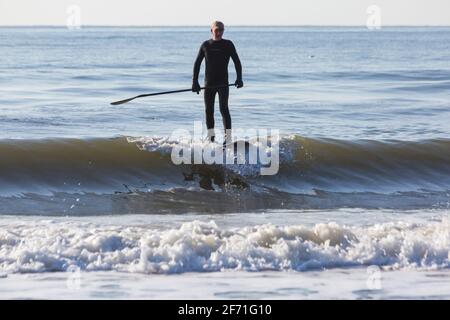 Poole, Dorset UK. 4 aprile 2021. Domenica di Pasqua. Tempo nel Regno Unito: Un inizio di giornata al sole che sembra essere un giorno pieno di sole e cielo blu, mentre la gente si dirige verso il mare a Poole spiagge per il lungo week-end di Pasqua in riva al mare. Paddleboarder godendo la pace prima che si affolgerà più tardi. Credit: Carolyn Jenkins/Alamy Live News Foto Stock