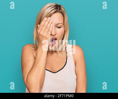 Media età donna caucasica che indossa abiti casual sbadigli stanchi coprendo metà faccia, occhio e bocca con mano. Faccia fa male nel dolore. Foto Stock