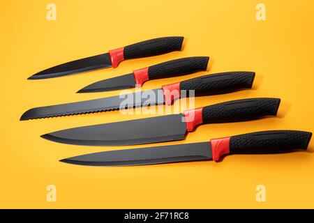 Impostare i coltelli da cucina con un manico nero su sfondo giallo. Foto Stock