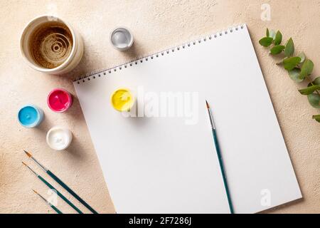 Ambiente di lavoro artistico con album di disegno, pennelli, taniche colorate Foto Stock