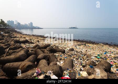 La costa di Mumbai è piena di rifiuti o di plastica, edifici moderni della città e Haji Ali Dargah sullo sfondo. Foto Stock