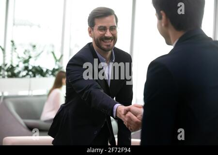 Sorridente partner commerciali maschi handshake alla riunione Foto Stock