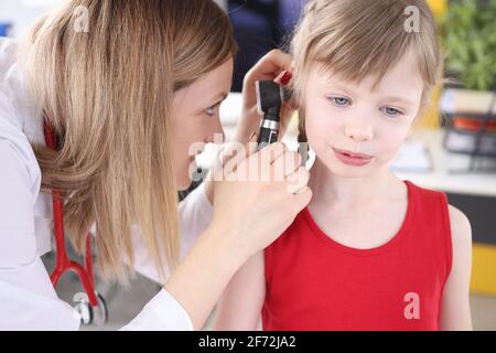 Il medico esamina l'orecchio con un otoscopio alla bambina Foto Stock