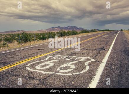 Lunga strada US con un cartello della Route 66 dipinto esso Foto Stock