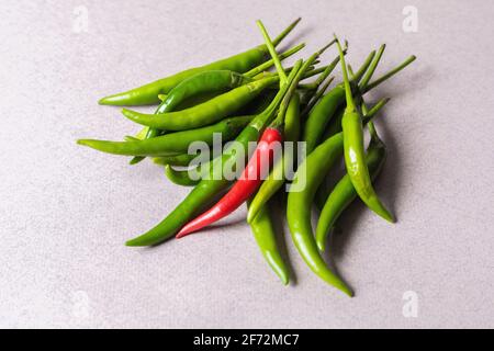 Scivola di peperoncino verde con uno rosso su uno sfondo chiaro. Vista dall'alto. Foto Stock