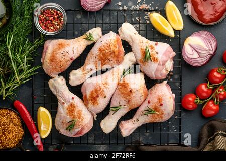 Bastoncini di pollo crudi con ingredienti per cucinare su fondo di pietra nera. Cibo di fondo, carne cruda con spezie al tavolo nero. Vista dall'alto. Foto Stock