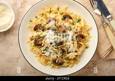 Pranzo risoni di pasta italiana, funghi, salsa, parmigiano, timo, aglio, olio d'oliva, in piastra bianca su ardesia, pietra o fondo di cemento. Vista dall'alto w Foto Stock