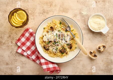 Pranzo risoni di pasta italiana, funghi, salsa, parmigiano, timo, aglio, olio d'oliva, in piastra bianca su ardesia, pietra o fondo di cemento. Vista dall'alto w Foto Stock