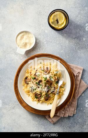 Pranzo risoni di pasta italiana, funghi, salsa, parmigiano, timo, aglio, olio d'oliva, in piastra bianca su ardesia, pietra o fondo di cemento. Vista dall'alto w Foto Stock