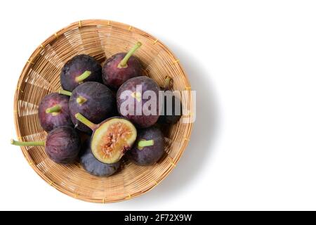 Frutta fresca di fico viola e fette in cesto di bambù isolato su sfondo bianco, fichi sono alti in calcio e contiene antiossidanti che aiuta a prevenire Foto Stock