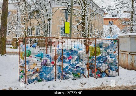 Tre antipolvere aperte piene di bottiglie e sacchetti di plastica. Rifiuti di plastica in grandi contenitori di rifiuti. Discarica della città in strada invernale. Foto Stock