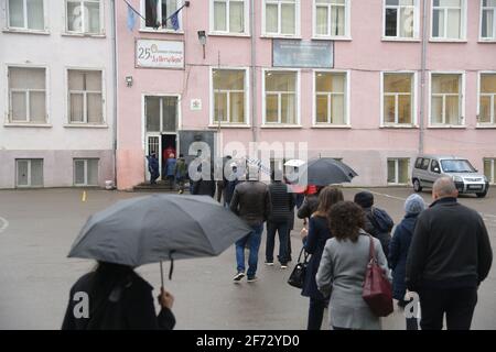 Sofia, Bulgaria - 4 aprile 2021: Una fila di elettori si è riunita di fronte a una scuola per dare il loro voto mantenendo la distanza sociale Foto Stock