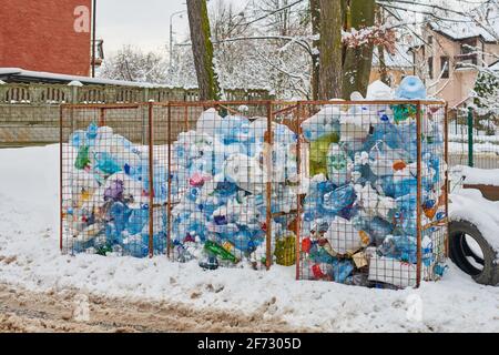 Tre antipolvere aperte piene di bottiglie e sacchetti di plastica. Rifiuti di plastica in grandi contenitori di rifiuti. Discarica della città in strada invernale. Foto Stock