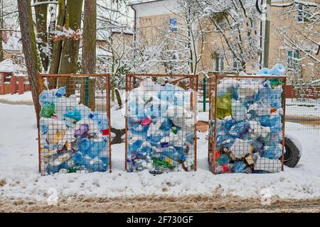 Tre antipolvere aperte piene di bottiglie e sacchetti di plastica. Rifiuti di plastica in grandi contenitori di rifiuti. Discarica della città in strada invernale. Foto Stock