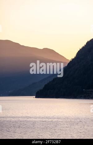 Atmosfera serale, sole che splende su montagne e colline al fiordo Innvikfjorden, Norvegia Foto Stock