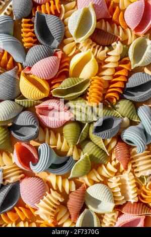 Diversi tipi di pasta secca colorata italiana come sfondo. Primo piano della macro. Foto Stock