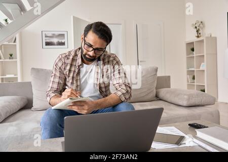 Uomo indiano che lavora o studia online da casa utilizzando un computer portatile. Foto Stock