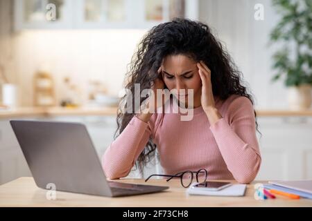 Concetto di mal di testa. Stressato Freelancer Signora che soffre di Emicrania dopo il lavoro sul computer Foto Stock