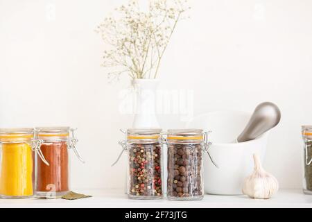Vasetti con spezie diverse e mortaio sul tavolo in cucina Foto Stock