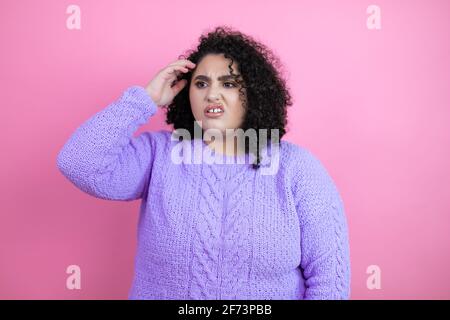 Giovane bella donna che indossa un maglione casual su sfondo rosa isolato confondere e meraviglia circa la domanda. Incerto con dubbio, pensando con la mano Foto Stock