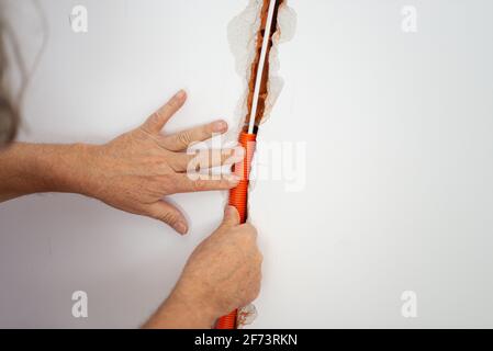 Posizionamento del tubo elettrico corrugato arancione in una parete nell'immagine concettuale del cantiere. Foto Stock