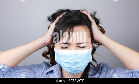 Donna che indossa una maschera protettiva contro il coronavirus. Impossibile ascoltare. Donna in una maschera che chiude le orecchie. Maschera medica, primo piano, selezione messa a fuoco, prec Foto Stock