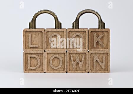 foto sul tema della lockdown. cubi di legno con la parola 'lockdown' e frammenti di due lucchetti chiusi, su sfondo bianco Foto Stock