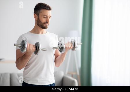 Closeup di bell'uomo bearded che fa workout dumbbell a casa Foto Stock