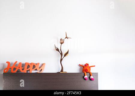 particolare della decorazione con il messaggio di felice un fiore di legno e una divertente mucca farcito d'arancia con fiori, tonalità arancio su legno colorato di wengè, w scuro Foto Stock