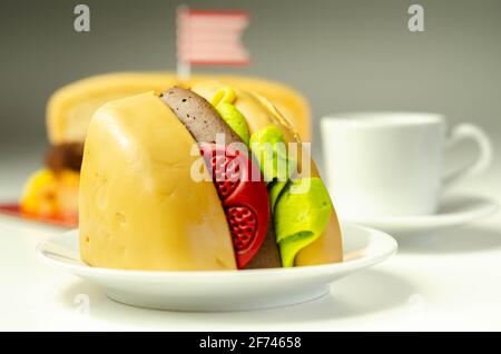 Pezzo della torta Burger, Madeira e torta stratificata di spugna di cioccolato, riempito con glassa ricoperta di glassa morbida e decorazioni di zucchero commestibile, torta i Foto Stock