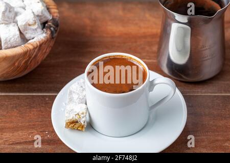 Caffè turco tradizionale servito in tazzine classiche con delizie turche. Sullo sfondo è presente una caffettiera in metallo. Foto Stock
