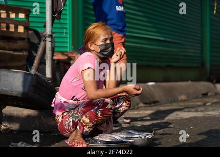 Una donna che vende pesce mentre indossa una maschera facciale durante Covid-19. Zona povera di Cebu City, Filippine Foto Stock