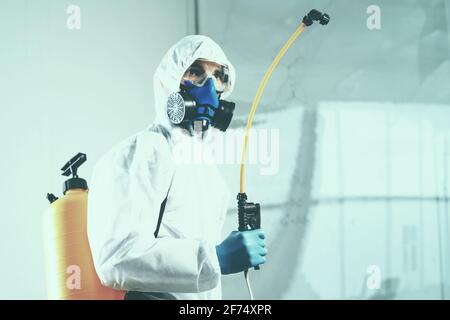 addetti ai servizi di decontaminazione che indossano dispositivi di protezione individuale, disinfettante a spruzzo. Foto Stock